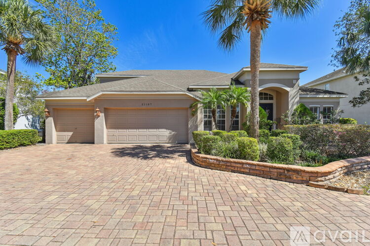 A house with a driveway and palm trees in front.