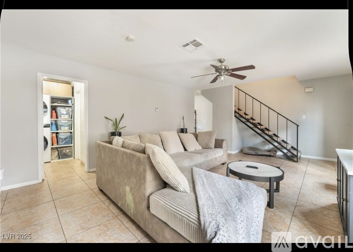 A living room with a couch, a coffee table, and a staircase.