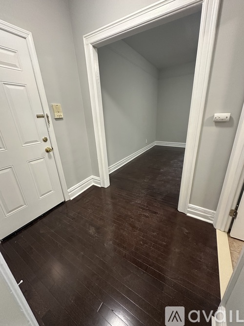 A hallway with a white door and a white wall.