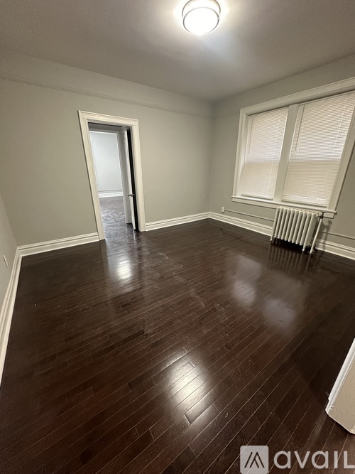 A room with wooden flooring and a window with blinds.