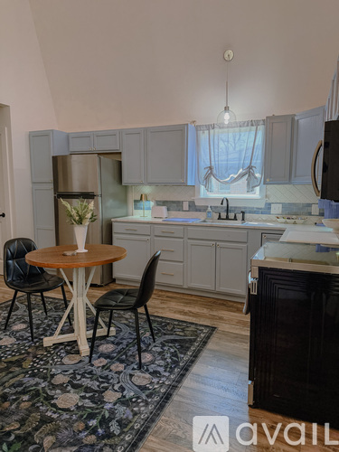 A kitchen with a table and chairs in front of a refrigerator.