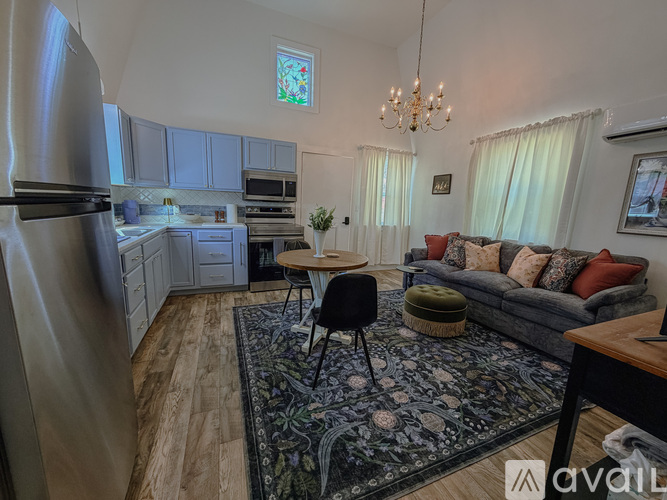 A kitchen with a refrigerator, a dining table with chairs, and a couch with pillows.