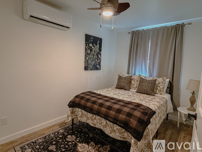 A bedroom with a bed, a ceiling fan, and a painting on the wall.