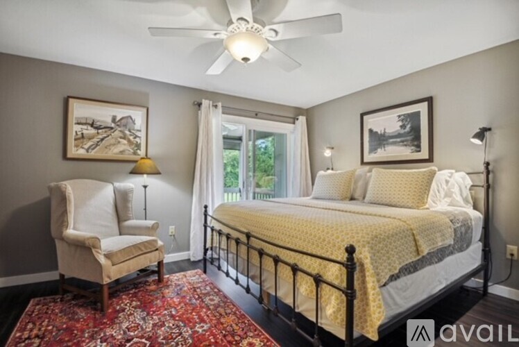 A bedroom with a bed, chair, and window.