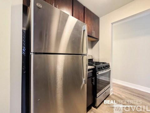 A stainless steel refrigerator in a kitchen with wooden cabinets.