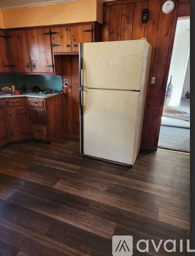 A white refrigerator stands in a kitchen with wooden cabinets.