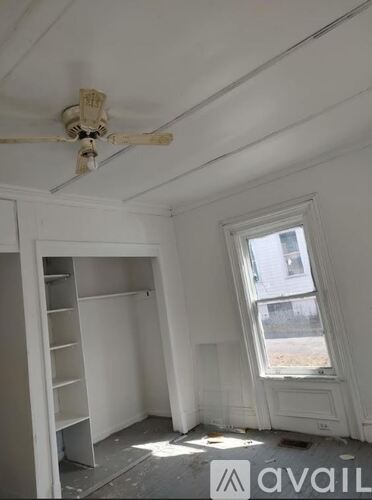 A room with a ceiling fan and a window.