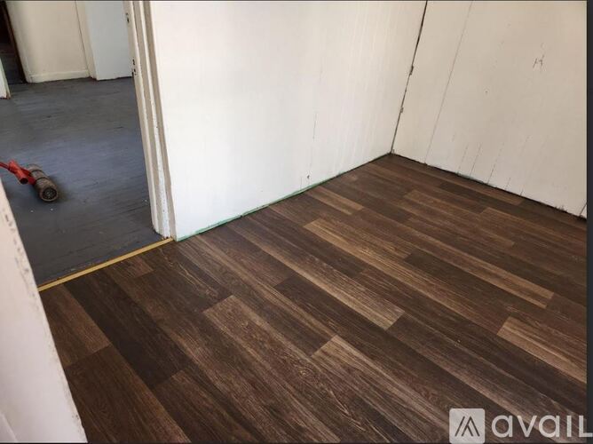 A room with wooden flooring and a red tool in the corner.