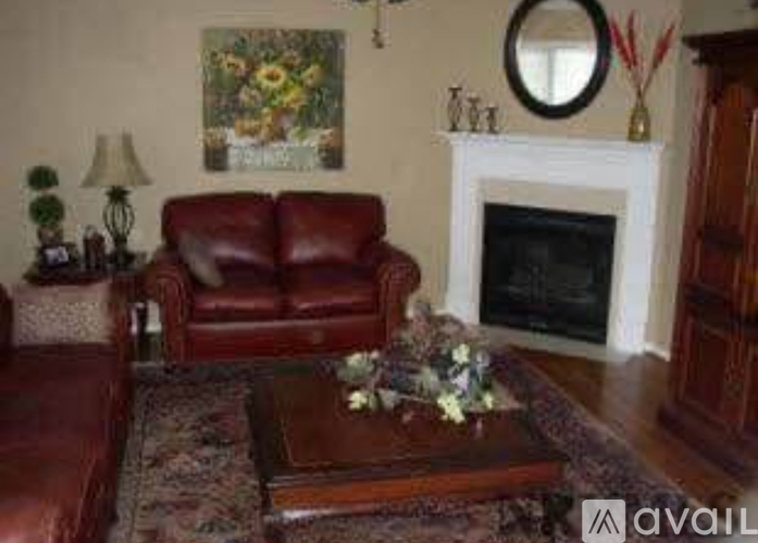 A living room with a red leather couch, a coffee table, and a fireplace.