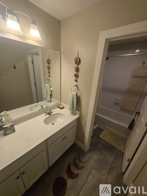 A bathroom with a sink, mirror, and a shower.
