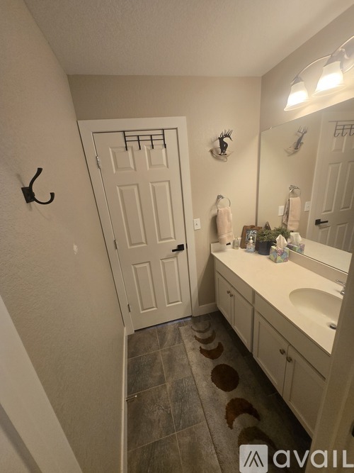 A bathroom with a white door, a sink, and a mirror.