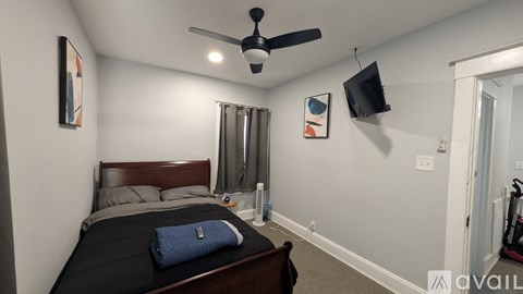 A bedroom with a bed, a ceiling fan, and a window with curtains.