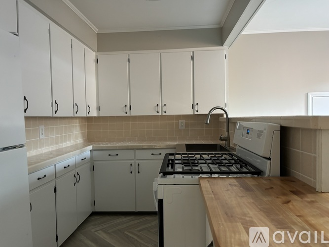 A kitchen with white cabinets and a wooden countertop.