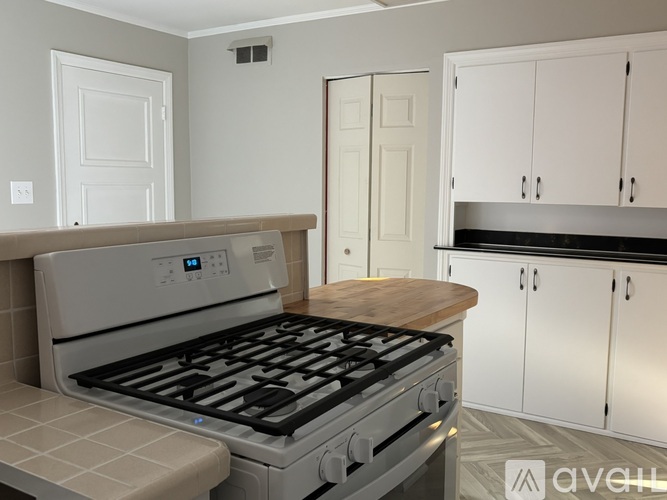 A modern kitchen with a stove top oven and white cabinets.