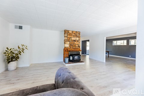 A living room with a grey couch and a stone fireplace.