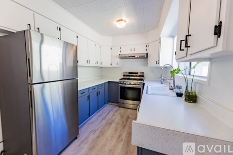 A kitchen with a stainless steel refrigerator and wooden flooring.