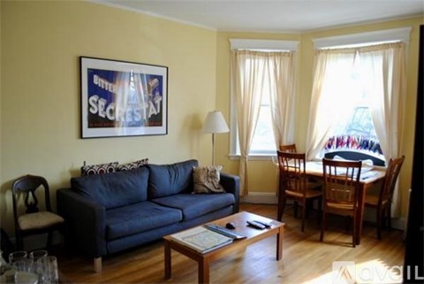 A living room with a blue couch and a framed picture on the wall.