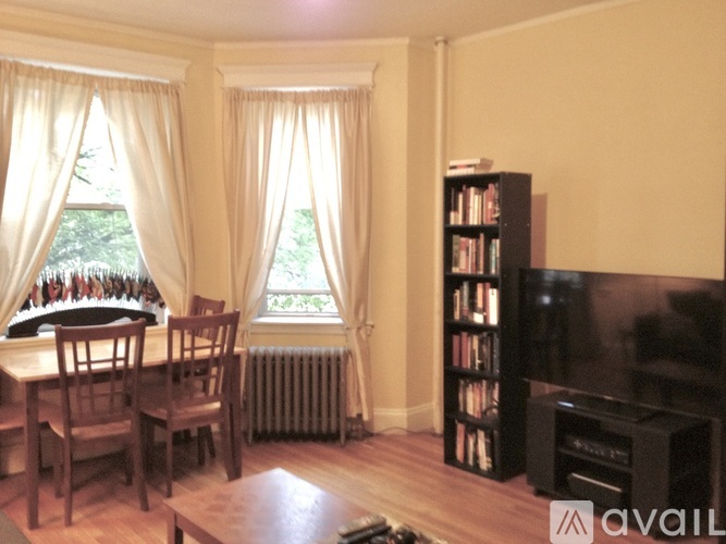 A living room with a television, a table with chairs, and a bookshelf.