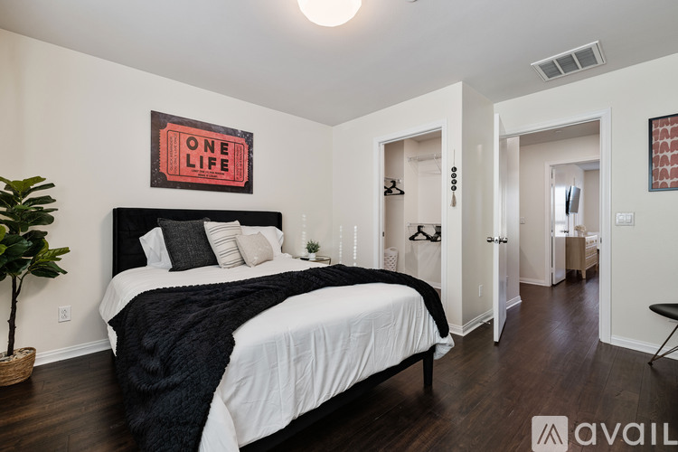 A bedroom with a large bed and a plant on the side table.