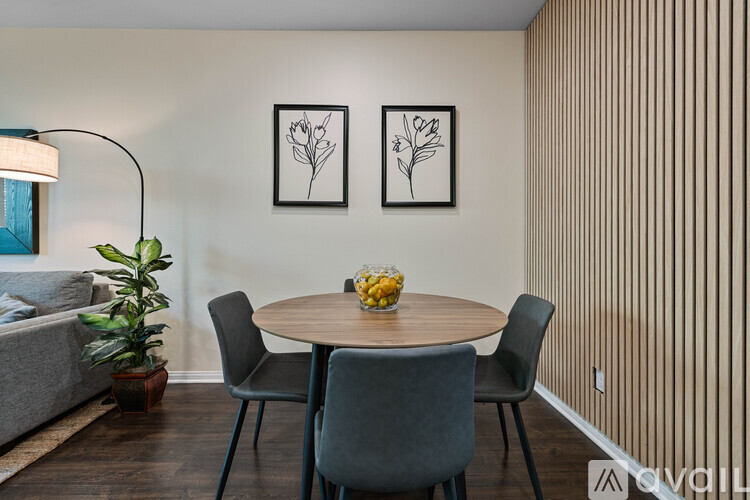 A dining room with a round table and grey chairs.
