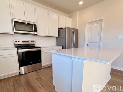 A kitchen with white cabinets and a stainless steel refrigerator.