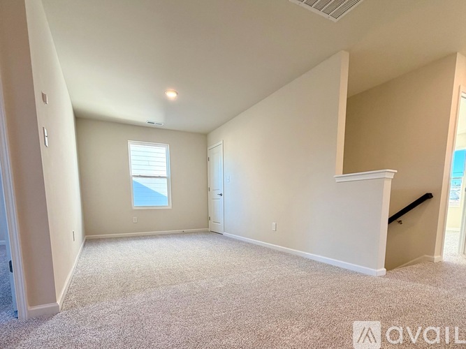 A spacious room with a window and carpeted floor.