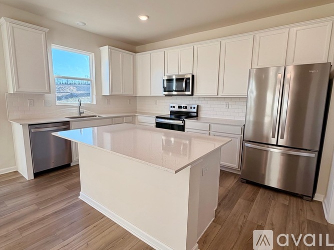 A kitchen with a white island and stainless steel appliances.