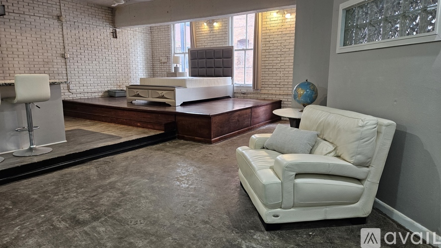 A white chair is in the foreground of a room with a brick wall and a wooden counter.