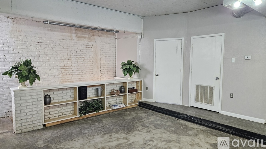 A room with a white brick wall and a wooden shelf with plants on it.