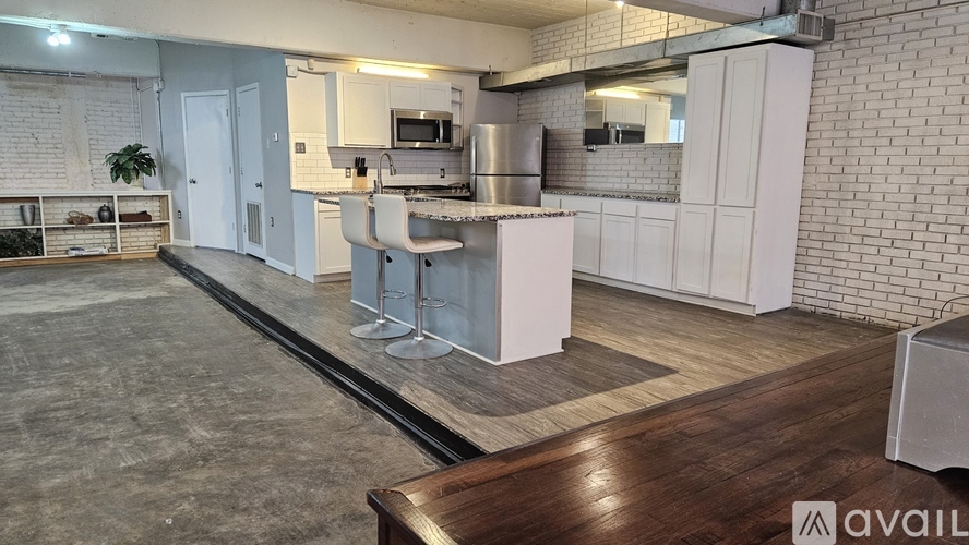 A kitchen with a white brick wall and a wooden floor.