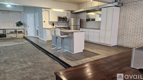 A kitchen with a white brick wall and a wooden floor.