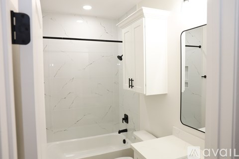 A white bathroom with a marble shower and a white vanity.