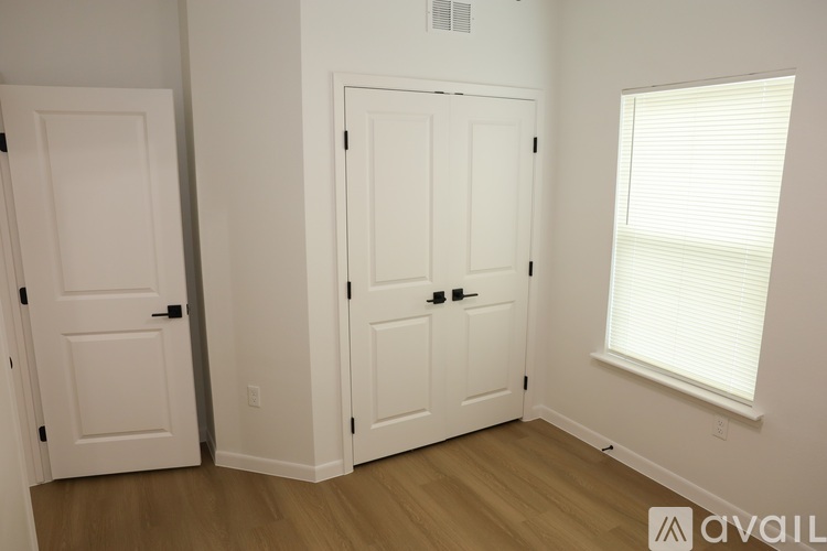 A room with two white doors and a window with blinds.