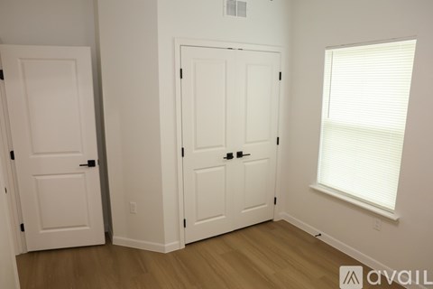 A room with two white doors and a window with blinds.