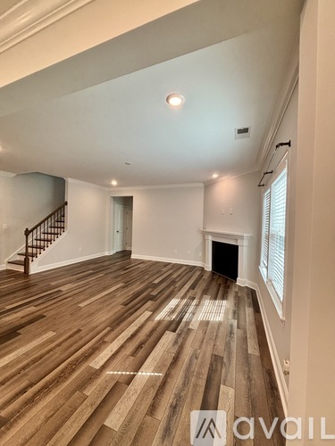 A spacious room with wooden flooring and a staircase.