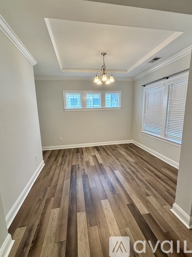 A room with wooden flooring and a chandelier.