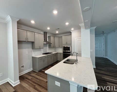 A kitchen with a white countertop and wooden flooring.
