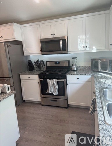 A kitchen with white cabinets and a stainless steel refrigerator.