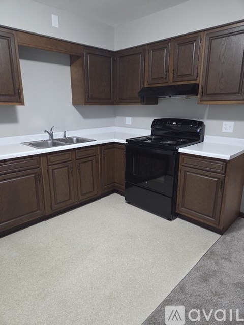 A kitchen with brown cabinets and a black stove top oven.
