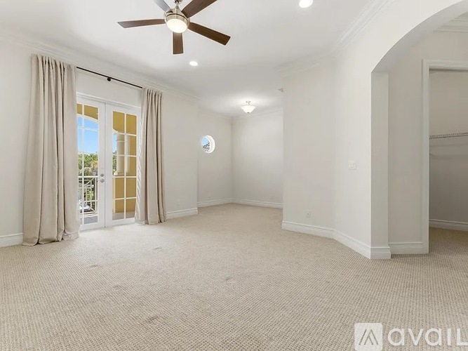 A spacious room with a ceiling fan and a sliding glass door.