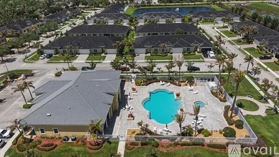 A bird's eye view of a residential area with houses, a swimming pool, and palm trees.