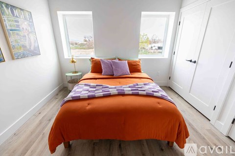 A bedroom with a bed covered in an orange bedspread and two pillows.