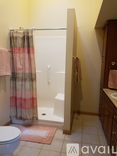 A bathroom with a toilet, a shower with a curtain, and a sink.