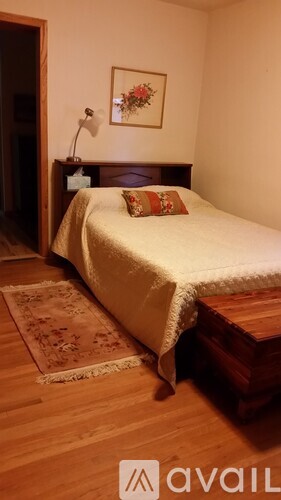 A bedroom with a bed, a lamp, and a picture on the wall.