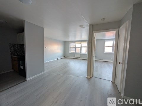 A spacious room with light wood flooring and white walls.