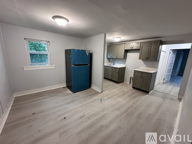 A kitchen area with a blue fridge and wooden flooring.