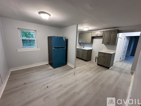 A kitchen area with a blue fridge and wooden flooring.