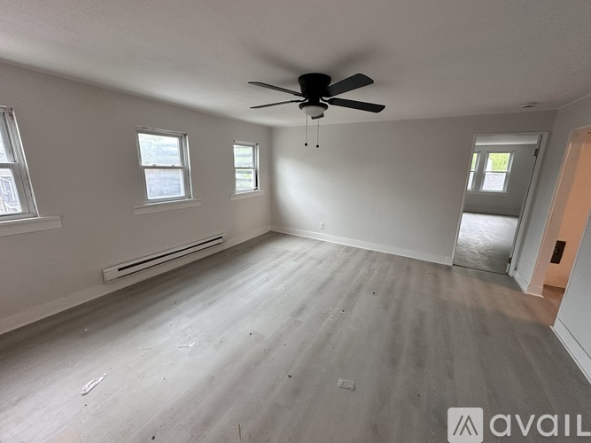 A spacious room with a ceiling fan and two windows.