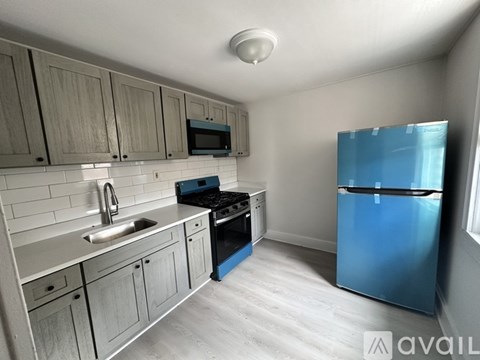 A kitchen with a blue refrigerator and wooden cabinets.