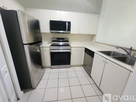 A kitchen with white cabinets and a black fridge.
